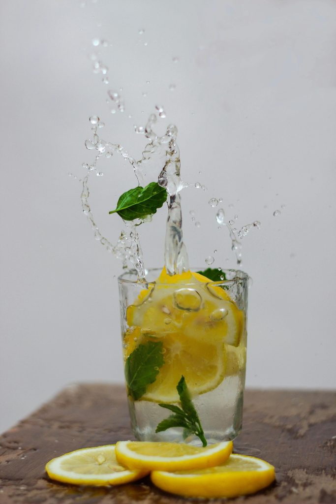 A glass of water with lemon slices and mint. A slice of lemon that is dropped into the glass makes water splash into the air. an image by suhairytriyadhi on Pexels