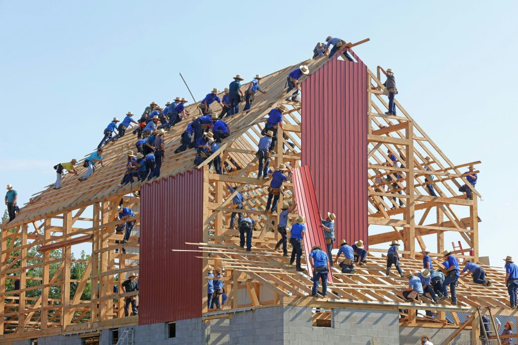 many people working on a wooden frame buidling - photo by randy fath at Unsplash