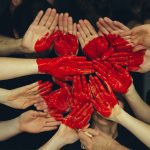 people's hands and red heart - photo by Tim Marshall - Unsplash